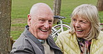 Happy senior couple outdoor and in love, spending quality time together in nature on a bench. Retirement and man and woman enjoy a relax day in a park or garden