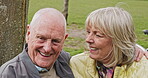 Happy senior couple outdoor and in love, spending quality time together in nature on a bench. Retirement and man and woman enjoy a relax day in a park or garden