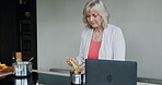 Cooking, senior woman and breakfast food in the kitchen of a house using a laptop online. Elderly person preparing a lunch on the stove at home