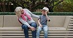 Senior woman and grandson bonding together in a garden with conversation and care. Love, putting on a hat and grandmother relax with family child