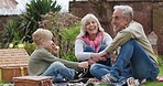 Grandson, family in garden on a picnic on holiday or vacation with a boy. Happy grandparents, man and woman with child bonding and relax