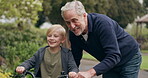 Grandfather teaching young boy to ride bicycle in garden, park and outdoor. Senior man helping happy kid with cycling on bike for fun, support and skill in nature