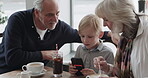 Cafe, breakfast with grandparents and a boy using his phone in the morning while eating food. Family, grandmother and grandfather with their child grandson in a coffee shop together for bonding