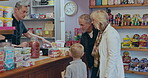 Grandparents, shopping and choice of sweets for a child at a shop or candy store counter. Senior man, woman and a boy kid or customer buying sugar treats from business owner or cashier on travel trip