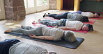 Corpse pose, relax and people in yoga class rest on mat in meditation for holistic, zen or wellness exercise. Group, stretching or lying on the floor and ground in gym with calm breathing practice