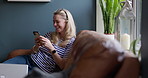 Cellphone, relax and mature woman networking on social media, mobile app or the internet at home. Smile, technology and female person scroll on a phone with message on sofa in living room of house.