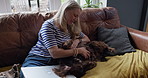 Woman, smile and stroke dog on sofa for smile with love, remote work and relax in living room at house. Person, pet and animal with belly rub, care or happy with laptop, talk and lounge couch in home