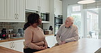 Home, communication and couple with age gap in kitchen, bonding and interracial love in retirement. Elderly man, young woman and chat with commitment in morning, relax together or care in apartment