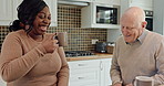 Talking, coffee and couple with support in kitchen, laughter and interracial love in retirement. Elderly man, young woman and talk with espresso drink in morning, relax together or funny in apartment
