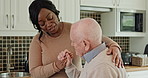 Care, conversation and caregiver with senior man in the kitchen of modern nursing home for assistance. Bonding, smile and black woman nurse with elderly male person in wheelchair at retirement house.