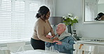 Caregiver helping senior man with jersey in the living room of modern nursing home for assistance. Bonding, smile and black woman nurse with elderly male person in wheelchair at retirement house.