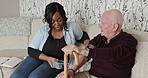 Blood pressure, healthcare or medicine with a nurse and old man on a sofa in the living room of  a home. Medical, retirement or checkup with a black woman caregiver and senior patient in an apartment