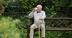 Happy senior man, coffee and park bench in garden for morning, relax or break at retirement home. Calm elderly male person drinking tea in mug or cup sitting with kane on outdoor chair in nature