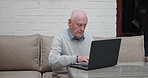 Computer, research and senior man on a sofa doing research on the internet in a retirement home. Technology, living room and elderly male person from Australia on a website with laptop at house.