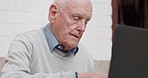 Search, typing and laptop by senior man on a sofa for streaming, research or social media in his home. Computer, retirement and old male with web communication, scroll or subscription service check