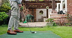 Golf, ball and senior man in backyard for sports, training and relax with hobby on artificial grass. Game, putting course challenge and club on green lawn with stroke, hit and swing in garden of home