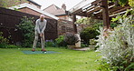 Golf, ball and senior man in garden for sports, training and relax with hobby on artificial grass. Game, putting course challenge and club on green lawn with stroke, hit and swing in backyard of home