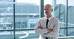Arms crossed, serious and thinking with business man at window of corporate office for planning. Future, idea and vision with confident employee in suit at professional workplace for career growth
