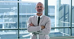 Arms crossed, thinking and vision with business man at window of corporate office for planning. Future, idea and smile with portrait of happy employee in suit at workplace for career development