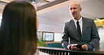 Executive, talking and receptionist at hotel front desk for conversation, appointment and check in info. Business man, help and concierge for guest registration, booking and reservation with mobile