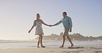 Couple, holding hands and walking by ocean, love and talking on vacation for romance on honeymoon. People, trust and playful on tropical island, support and drag husband by waves on weekend date