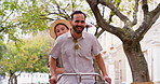Date, bicycle and summer with couple, smile and together on street in town for travel. Man, woman and cycling for tourist, holiday and flying hat for eco friendly city sightseeing for windy adventure