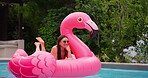 Holiday, relax and woman in pool with inflatable, smile and float in water with flamingo at resort. Summer, weekend and happy girl swimming at hotel with sunglasses, celebration and fun vacation trip