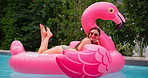 Summer, relax and woman in pool with inflatable, smile and float in water with flamingo at resort. Holiday, weekend and happy girl swimming at hotel with sunglasses, celebration and fun vacation trip