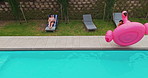 Drone, man and jump on float in swimming pool outdoor of summer vacation, luxury resort and hospitality trip. Aerial, people and energy of inflatable flamingo, water and holiday destination at lodge 
