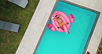 Man, relax and floating in swimming pool outdoor for summer vacation, luxury resort and hospitality trip. Aerial, male person and rest for inflatable flamingo, water and holiday destination at lodge 