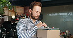 Small business, entrepreneur and man with tablet, online order and checklist for stock with stylus. Coffee shop, inventory and preparing for delivery with tech, distribution and  person with boxes