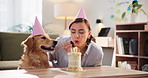 Blowing candles, cake and dog with excited woman in living room of apartment together for celebration. Love, party and smile of happy pet owner with labrador in apartment for bonding or milestone