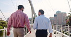 Collaboration, tablet and walking with business people on bridge in city for conversation from back. Commute, partnership and teamwork with employee men outdoor in urban town together for planning