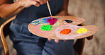 Hands, painter and palette in home studio with color, mix and creative process, tools and talent for project. Person, artist and wood tray with brush, equipment and hobby with painting at apartment