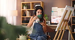 Coffee, artist and woman with headphones by canvas for streaming sound or inspiration audio. Drink, painter and listening to music for creative hobby, thinking and idea with art design in home studio