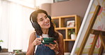 Coffee, painter and woman with music by canvas for streaming sound or inspiration audio. Drink, happy artist and listen to headphones for creative hobby, thinking or satisfied with art in home studio