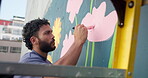 Painting, wall and flowers with man in city for street artist, urban design or environment activist. Mural, sustainability awareness and creative with painter outdoor for earth day, color and culture