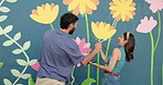 Playful, couple and painting with wall art of mural process, creativity and decoration of community project. Man, woman and laughing with artist brush, flower aesthetic and bonding of diy inspiration