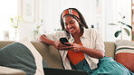 African woman, phone and texting on sofa in home, contact or relax with scroll on web chat in living room. Girl, smartphone and click on mobile app for notification, happy or social network in house