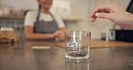Hand, person and money for tips at cafe of customer gratitude, community contribution and payment method. Closeup, client and jar for cash transaction, good service and staff reward of finance income