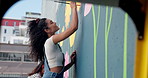 Smile, woman and painting mural on wall with creative decoration, community project and artistic freedom. People, artist and diy with public art, flower design and local culture for therapeutic hobby