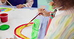 Hands, child and painting art in classroom with creative lesson, drawing rainbow and kindergarten learning. Artist, kid and picture with fun activity, artwork project and motor growth for education