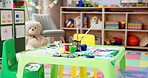 Kindergarten, art and table in empty classroom for education, learning and growth at daycare. Paint, drawing and playroom in school with toys, stationery or furniture for creative child development