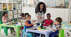 Teaching, children and painting in classroom, woman and education for group in daycare and students. Talking, teacher and learning with color for artwork, growth and development for kids in preschool