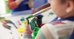 Hands, child and painting fingers in classroom of creative lesson, drawing picture and kindergarten learning. Student, brush and messy with fun activity, artwork project and motor growth of education