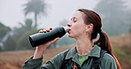 Trekking, woman and drinking coffee in nature on vacation, thinking and relax with fog. Hiking, flask and happy person in woods with hot beverage, tea and travel with reflection or vision outdoor
