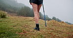 Hiking stick, legs and person walking outdoor for travel, adventure and journey with fog on mountain. Trip, trekking pole and shoes of woman in nature for vacation, balance and back for exploration