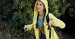 Trees, hiking and woman with stick, raincoat and outdoor adventure holiday on winter weekend. Walking, hill and girl in woods with morning trekking in forest, travel vacation and explore in nature