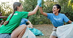 Volunteer, team and cleaning nature with high five, support and excited for community service. People, environment care and gesture at trash with collection, social responsibility and NGO development
