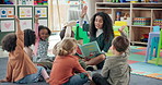 Woman, teacher and storytelling with hands raised in nursery for question, engagement or interaction. Female person, educator or instructor with elementary kids, answer or book for listening activity